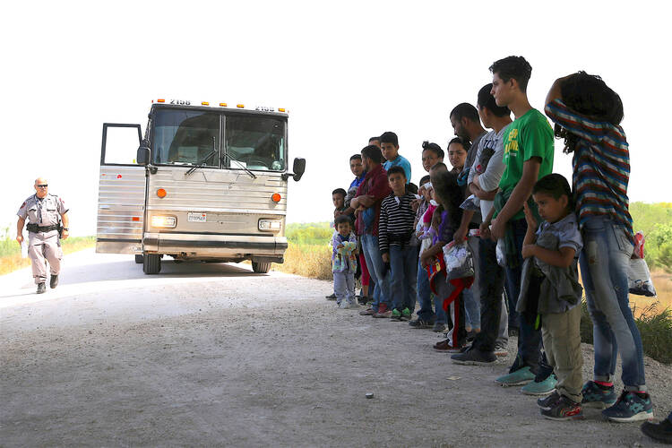 Immigrants turn themselves in to Border Patrol agents on April 2 after illegally crossing the border from Mexico into the U.S., and wait to be transported to processing center near McAllen, Tex. (CNS photo/Loren Elliott, Reuters) 