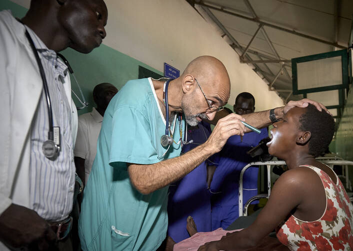 Dr. Tom Catena, a Catholic lay missionary from the United States, examines a patient during rounds in late April at the Mother of Mercy Hospital in Gidel, a village in the Nuba Mountains of Sudan. The Catholic hospital, at which Catena is often the only physician, is the only referral hospital in the war-torn area. (CNS photo/Paul Jeffrey)