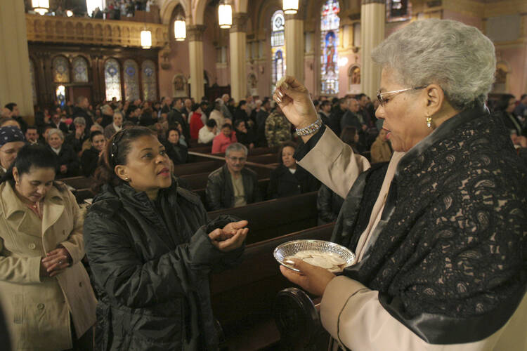An extraordinary minister of the holy Eucharist distributes Communion during Mass at Transfiguration Church in the Williamsburg section of Brooklyn, N.Y.  (CNS photo/Gregory A. Shemitz)