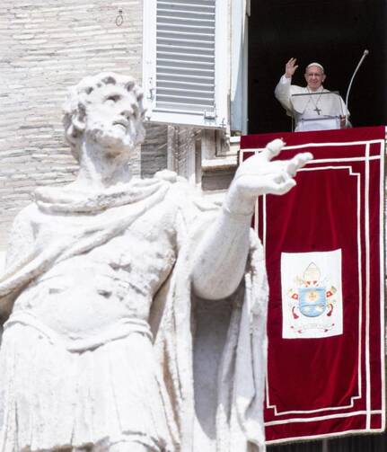 Pope Francis waves as he leads the Angelus from the window of his studio overlooking St. Peter's Square at the Vatican Aug. 15, the Feast of the Assumption.