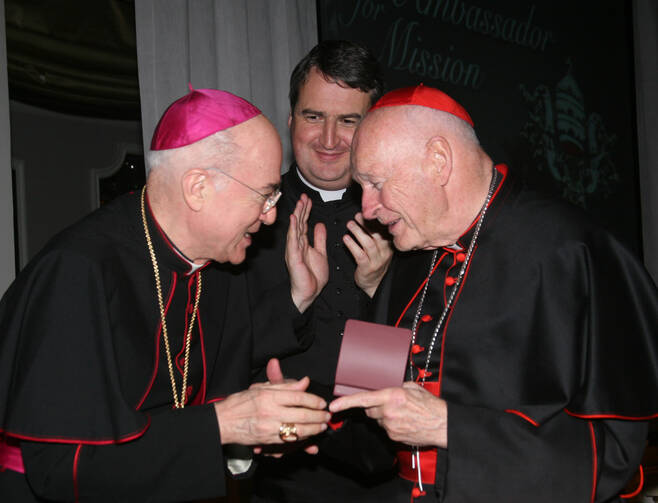 Archbishop Carlo Maria Vigano, then nuncio to the United States, congratulates then-Cardinal Theodore E. McCarrick of Washington at a gala dinner sponsored by the Pontifical Missions Societies in New York in May 2012. The archbishop has since said Cardinal McCarrick already was under sanctions at that time, including being banned from traveling and giving lectures. Oblate Father Andrew Small, center, director of the societies, said Archbishop Vigano never tried to dissuade him from honoring the cardinal at 