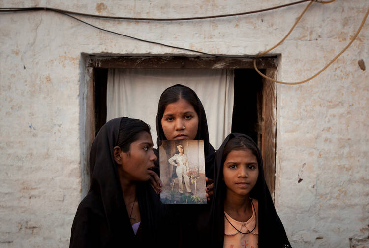 The daughters of Asia Bibi pose in 2010 with an image of their mother outside their residence in Sheikhupura, Pakistan. (CNS photo/Adrees Latif, Reuters) 