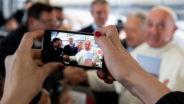 A journalist takes a cell phone photo of Pope Francis Jan. 23, 2019, aboard his flight from Rome to Panama for World Youth Day. (CNS photo/Vatican Media)