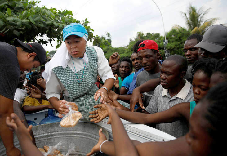 A member of the Missionaries of the Risen Christ provides migrants with food in Tapachula, Mexico, May 11, 2019. Some African and Haitian migrants have been stranded in southern Mexico for two months. (CNS photo/Andres Martinez Casares, Reuters)