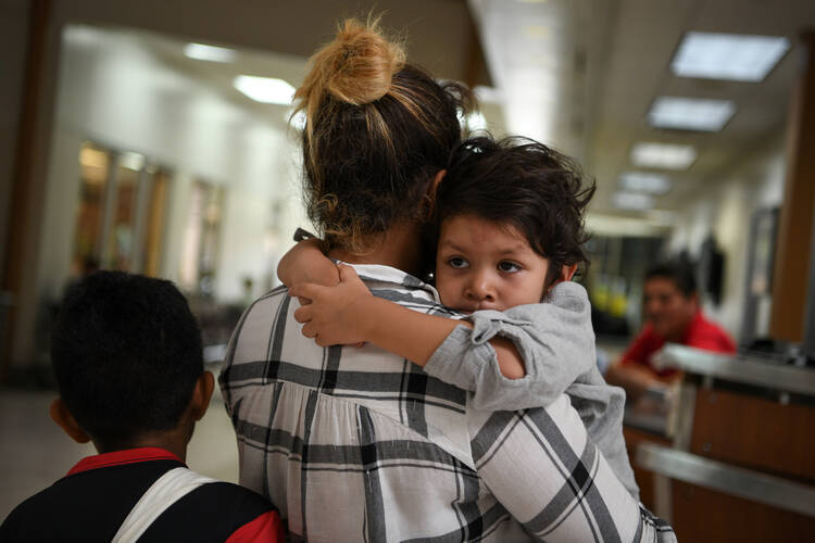 A Honduran asylum seeker released from detention holds her son while waiting at a bus depot in McAllen, Texas, on May 19. (CNS photo/Loren Elliott, Reuters)