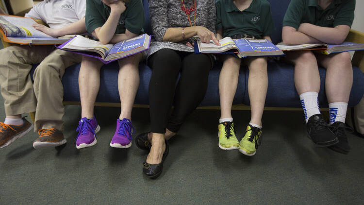 A teacher at Holy Name of Jesus Catholic School in Henderson, Ky., helps third-grade students with a reading lesson on March 28, 2019. A new document from the Vatican Congregation on Education states that Catholic schools and parents must help teach children that gender is fixed from birth. (CNS photo/Tyler Orsburn)