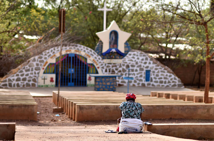 A displaced Christian woman prays in front of a grotto with a statue of Mary in Kaya, Burkina Faso, May 16, 2019. Bishop Laurent Dabire of Dori, president of the bishops' conference of Burkina Faso and Niger, has urged international action to stop the massacre of Christians by foreign-backed Islamist groups. (CNS photo/Anne Mimault, Reuters) 