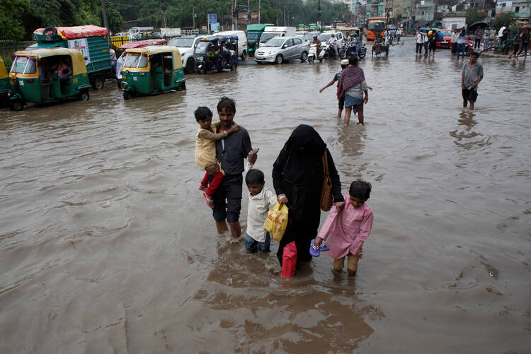 A family wades through a flooded street during heavy rains in New Delhi, India, Aug. 6, 2019. Catholic churches and other institutions opened their doors to people stranded in Mumbai and surrounding areas because transportation routes were blocked by high water and debris. (CNS photo/Adnan Abidi, Reuters) 