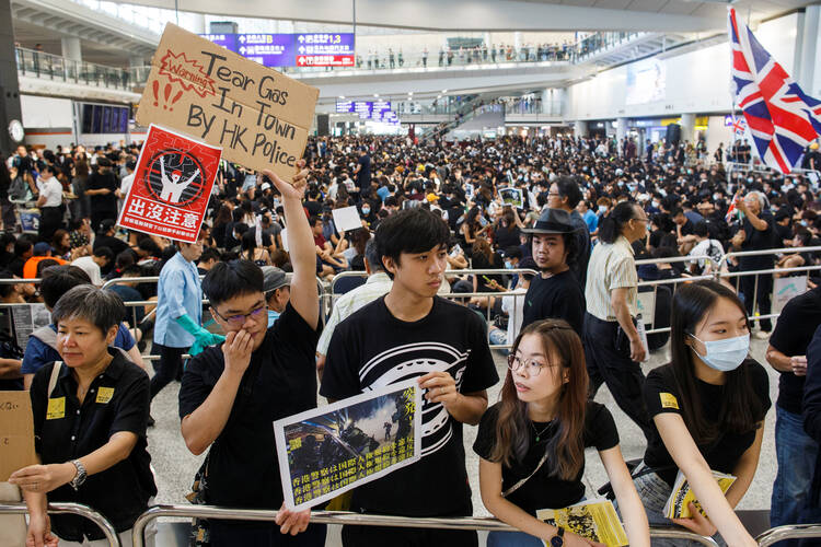Anti-extradition bill protesters hold placards for arriving travelers during a protest at Hong Kong International Airport Aug. 9, 2019. More than 1,000 Catholics prayed during a candlelight vigil outside the Cathedral of the Immaculate Conception Aug. 8 for Hong Kong to solve its political crisis in a nonviolent manner. (CNS photo/Thomas Peter, Reuters)