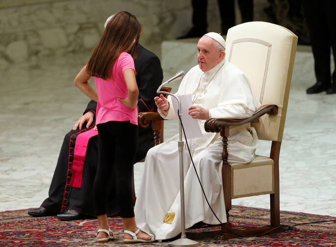 A girl talks with Pope Francis during his general audience in Paul VI hall at the Vatican Aug. 21, 2019. The pope allowed the girl with an undisclosed illness to move around undisturbed clapping and dancing on the stage.