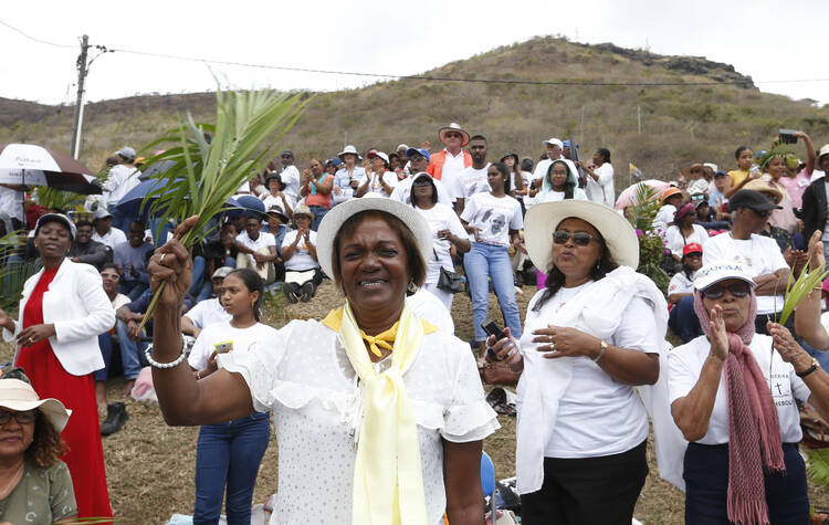 A woman waves palm fronds as people wait for the arrival of Pope Francis to celebrate Mass at the monument to Mary, Queen of Peace in Port Louis, Mauritius, Sept. 9, 2019. (CNS photo/Paul Haring)