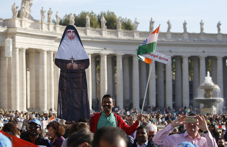 A man holds a life-size cutout of new St. Mariam Thresia Chiramel Mankidiyan of India before the canonization Mass for five new saints celebrated by Pope Francis in St. Peter's Square at the Vatican on Oct. 13. (CNS photo/Paul Haring)