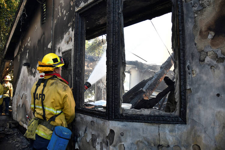 A firefighter douses water on a house after it was burned by the wind-driven Getty Fire outside Los Angeles Oct. 28, 2019. By Oct. 29, the fire had burned more than 600 acres and was 5% contained, according to the Los Angeles Fire Department. (CNS photo/Gene Blevins, Reuters) 