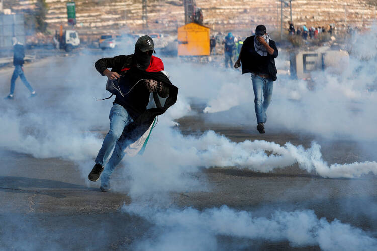 Palestinian demonstrators run away from tear gas fired by Israeli forces on Nov. 16, during an anti-Israel protest near the Jewish settlement of Beit El in the Israeli-occupied West Bank. (CNS photo/Mohamad Torokman, Reuters) 