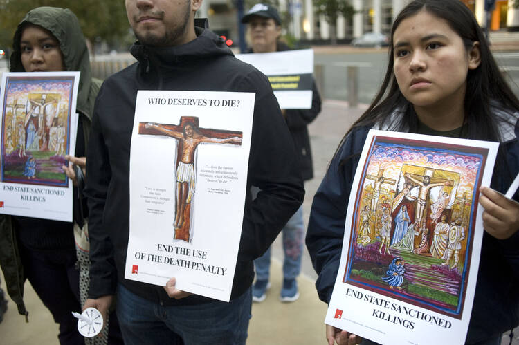 People hold signs during a candlelight prayer vigil Dec. 8, 2019, held to oppose the Trump administration's plan to reinstate the federal death penalty. (CNS photo/David Maung)