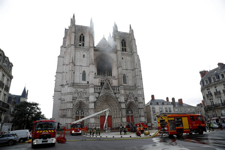 French firefighters gather at the scene of a blaze at the Cathedral of Sts. Peter and Paul in Nantes July 18, 2020. Police are investigating the incident as arson because the fire started in three different places. (CNS photo/Stephane Mahe, Reuters)