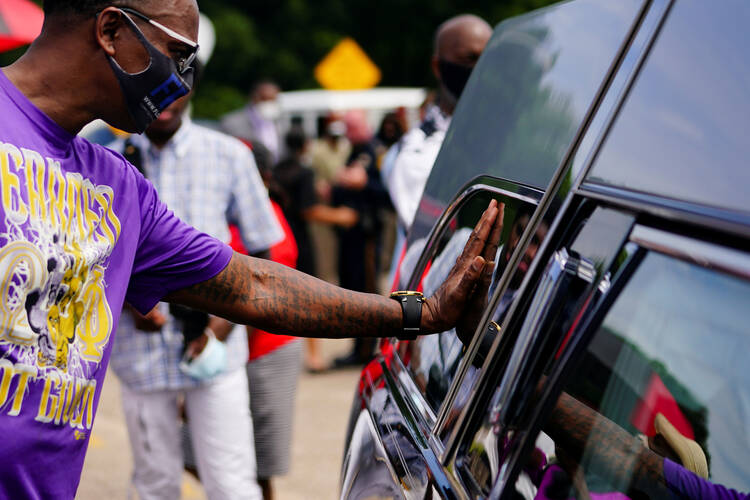 A man in Selma, Ala., places his hand on the hearse carrying the body of the late Rep. John Lewis, D-Ga., after it was carried across the Edmund Pettus Bridge July 26, 2020. The civil rights movement legend who was a colleague of the Rev. Martin Luther King Jr. died July 17, 2020. He was 80. (CNS photo/Elijah Nouvelage, Reuters) 