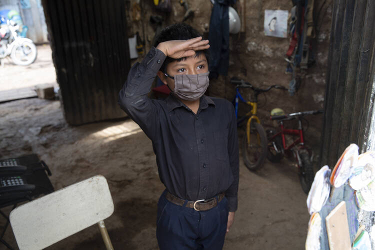 Standing just inside the doorway of his home in a black button down shirt tucked into navy blue trousers, 11-year-old Oscar Rojas greets his teacher Gerardo Ixcoy in Santa Cruz del Quiche, Guatemala, on July 15. “Teacher Lalito only comes for a little while to teach me, but I learn a lot.” (AP Photo/Moises Castillo)