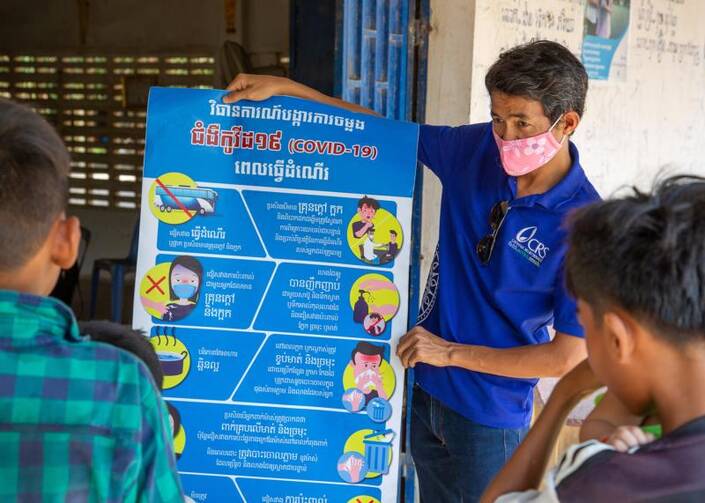 A Catholic Relief Services staff member in Cambodia explains the latest COVID-19 information to a small group of village leaders. (CNS photo/Jennifer Hardy)