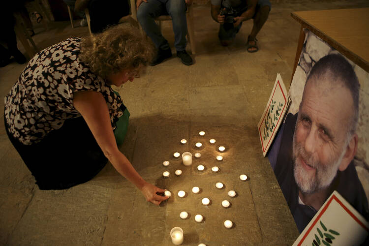 A Lebanese woman lights a candle in front of a portrait of Italian Jesuit priest, Father Paolo Dall'Oglio, at the St. Joseph Church in Beirut, Lebanon, in July 2015. (AP Photo/Hussein Malla)