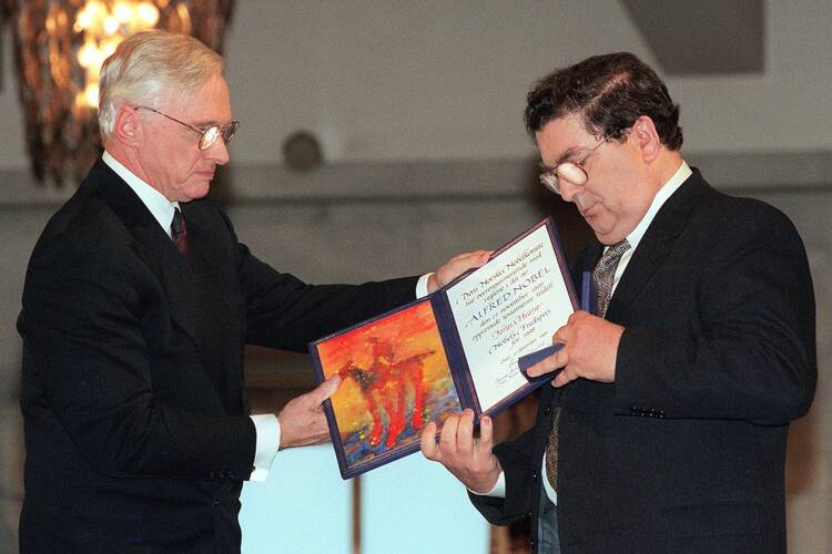 In this Dec. 10, 1998 file photo, John Hume, right, looks at the Nobel Peace Prize diploma which he received from Francis Sejersted, left, chairman of the Norwegian Nobel Peace Prize Committee during the award ceremony in Oslo Town Hall. (AP Photo/Bjoern Sigurdsoen/NTB/POOL)