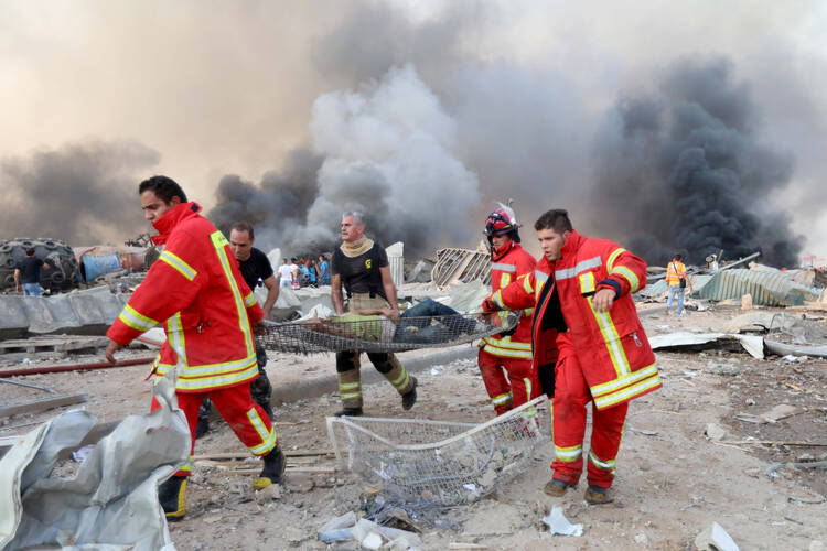 Firefighters carry an injured man following explosions in Beirut Aug. 4, 2020. Two massive explosions near the port of the Lebanese capital injured dozens of people and shattered windows in buildings blocks away. (CNS photo/Mohamed Azakir, Reuters)