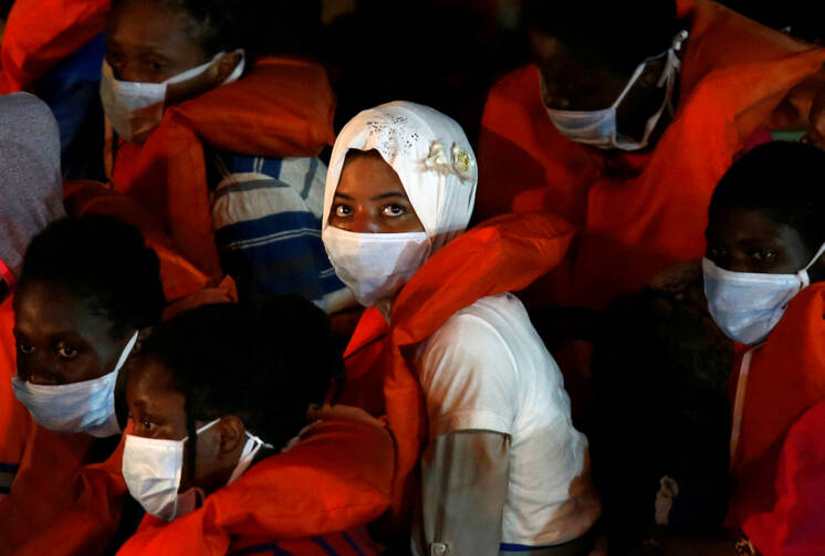 Rescued migrants look out from an Armed Forces of Malta vessel upon their arrival in Valletta, Malta, Aug. 3, 2020. (CNS photo/Darrin Zammit Lupi, Reuters)