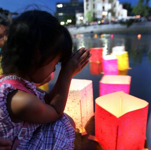 A girl prays after releasing a paper lantern on the Motoyasu River facing the gutted Atomic Bomb Dome in Hiroshima, Japan, Aug 6, 2020, the 75th anniversary of the U.S. dropping the atomic bomb on Hiroshima. (CNS photo/Yuriko Nakao, Reuters)