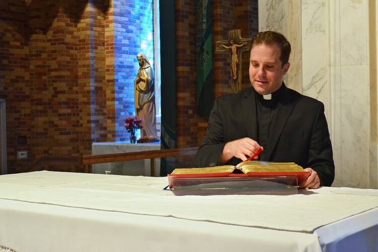 Rev. Matthew Hood thumbs through a missal at the altar of St. Lawrence Parish in Utica, Mich., on Aug. 21, 2020. Finding out he wasn’t a priest was a painful realization, but it came with the grace of knowing God’s providence, he said. (CNS photo/Michael Stechschulte, Detroit Catholic)