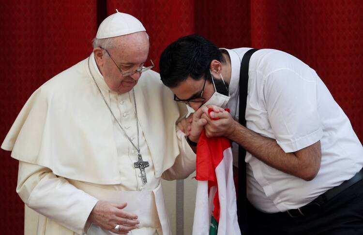 A masked Maronite Father Georges Briedi kisses the hand of Pope Francis as the two men hold a Lebanese flag during the pope's weekly general audience at the Vatican Sept. 2, 2020. (CNS photo/Guglielmo Mangiapane, Reuters)