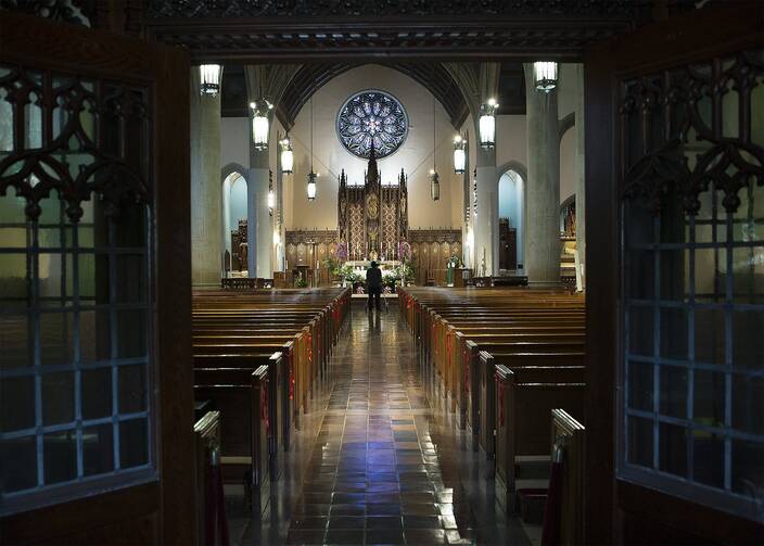 A cameraman films Father Kevin Kennedy at the altar at St. Gabriel Catholic Church in Washington, D.C., on July 11, for a live-streamed Mass. (CNS photo/Tyler Orsburn)