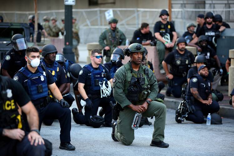 Police officers in Atlanta kneel with protesters on June 1, following a white police officer’s killing of George Floyd, an African American, in Minneapolis on May 25. (CNS photo/Dustin Chambers, Reuters)
