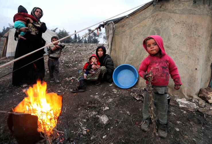 A file photo shows displaced Syrian women and children who fled from Idlib province gathering around a fire in Afrin. A majority of Syrians who have had to flee their homeland are Christians. (CNS photo/Khalil Ashawi, Reuters)