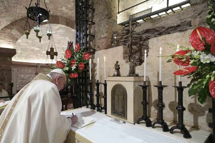 Pope Francis signs his new encyclical, "Fratelli Tutti, on Fraternity and Social Friendship" after celebrating Mass at the Basilica of St. Francis in Assisi, Italy, Oct. 3, 2020. (CNS photo/Vatican Media)