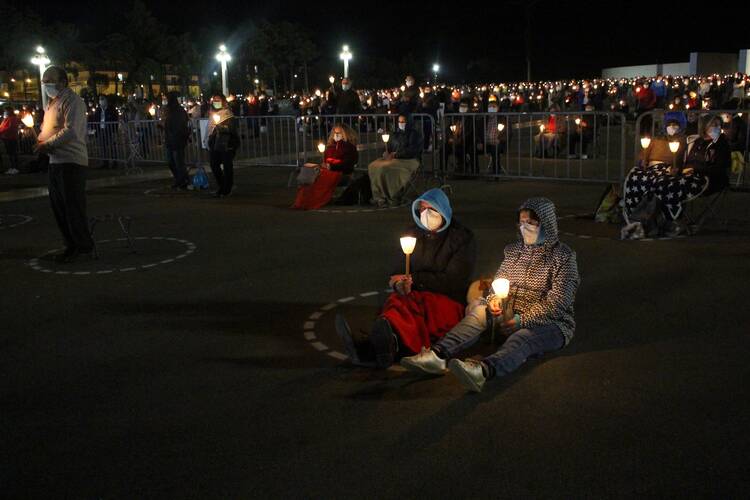 Pilgrims hold candles and pray while maintaining social distancing at the Marian shrine of Fatima in central Portugal Oct. 12, 2020, during the COVID-19 pandemic. (CNS photo/Pedro Nunes, Reuters)
