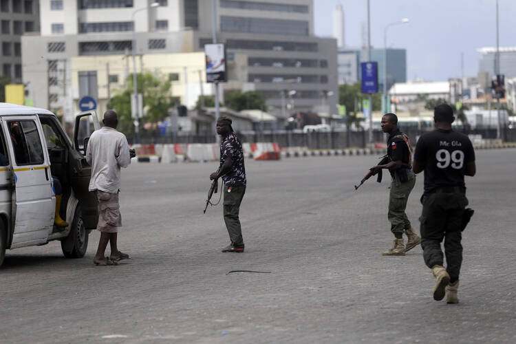 Police officers stop and search a bus carrying passengers around Lekki toll gate in Lagos Friday, Oct. 23, 2020. Resentment lingered with the smell of charred tires Friday as Nigeria's streets were relatively calm after days of protests over police abuses, while authorities gave little acknowledgement to reports of the military killing at least 12 peaceful demonstrators earlier this week. (AP Photo/Sunday Alamba)
