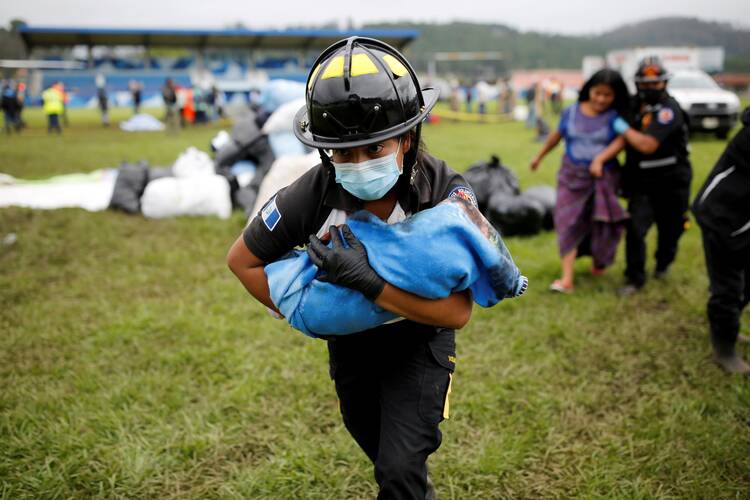 A firefighter carries a baby rescued along with her mother from an area affected by mudslides in San Cristobal Verapaz, Guatemala, Nov. 7, 2020, caused by the remains of Hurricane Eta. (CNS photo/Luis Echeverria, Reuters)