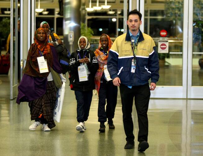 Somali refugees are escorted by a United Airlines representative as they arrive at the airport on Feb. 13, 2018, in Boise, Idaho. (CNS photo/Brian Losness, Reuters)