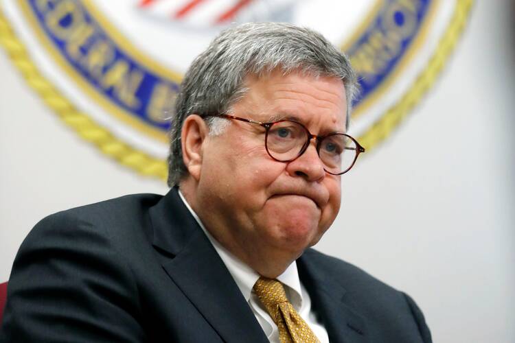 AG William Barr pursing his lips while wearing a dark suit and a golden tie in front of U.S. office seal in the background