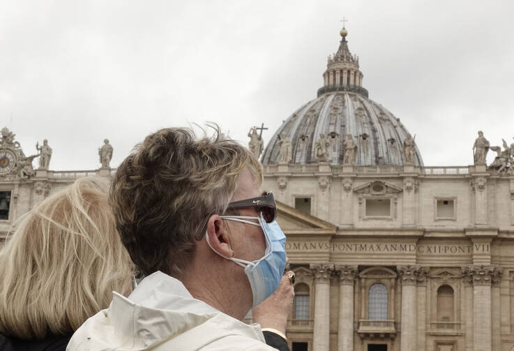 A woman wearing a mask for protection from the coronavirus watches as Pope Francis leads the Angelus from the window of his studio overlooking St. Peter's Square at the Vatican March 1, 2020. (CNS photo/Paul Haring) 