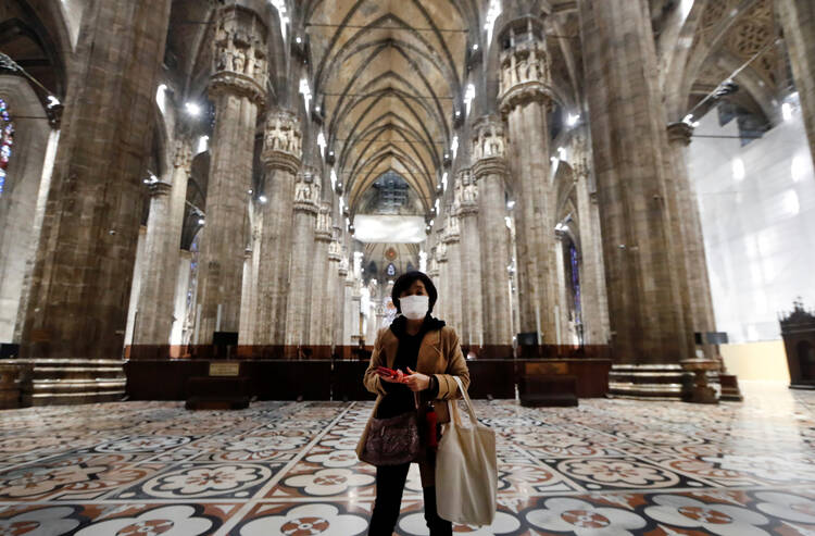A tourist wearing a protective mask visits Milan's famed cathedral, commonly referred to as the "Duomo," as it reopened to the public March 2, 2020, for the first time since the coronavirus outbreak. (CNS photo/Yara Nardi, Reuters) 