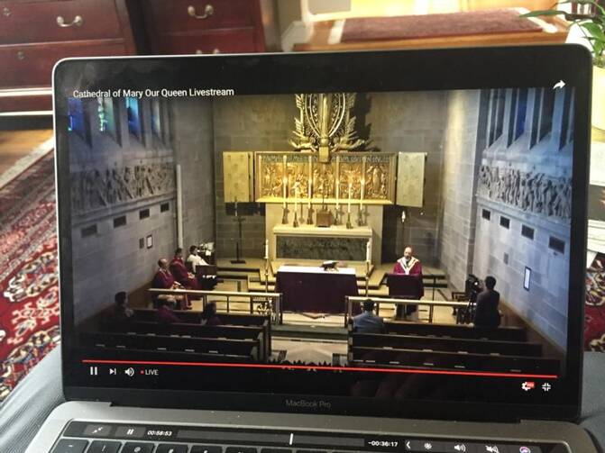 A viewer watches a livestream Mass from the Cathedral of Mary Our Queen in Baltimore celebrated by Baltimore Archbishop William E. Lori and a few concelebrants March 15, 2020. All Sunday Masses in the Archdiocese of Baltimore were canceled amid coronavirus pandemic concerns. (CNS photo/Ann M. Augherton, Arlington Herald)