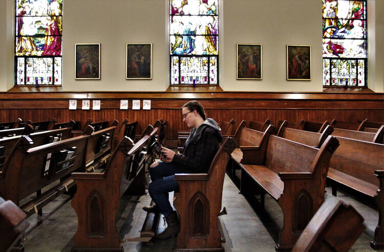 A woman reads a prayer book in the sanctuary of St. Mary Church in Appleton, Wis., on March 18,. Bishop David L. Ricken of Green Bay announced on March 17 that all public Masses in the diocese are suspended for the next four to eight weeks due to the coronavirus pandemic. (CNS photo/Brad Birkholz)