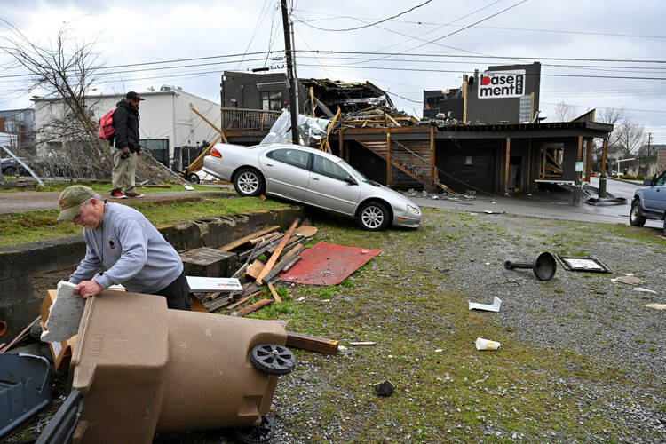 A man in Nashville, Tenn., picks up debris near his business March 3, 2020, after a tornado hit the area. In the Nashville Diocese, people and parishes, as well as Catholic Charities of Tennessee, are balancing their response to the coronavirus with ongoing tornado recovery. (CNS photo/Harrison McClary, Reuters