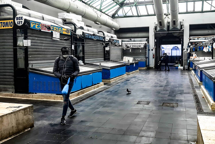 A man walks past the shuttered stalls of fishmongers at Rome's Piazza Vittorio market on March 25.  (CNS photo/Nancy McNally) 