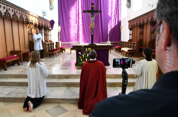 A cameraman films Father Herbert Gugler celebrating a Good Friday liturgy, livestreamed on the internet, at the Assumption of the Virgin Mary Catholic Church in Aichach, Germany, April 10, 2020. The church was closed to the public amid the coronavirus pandemic. (CNS photo/Andreas Gebert, Reuters)