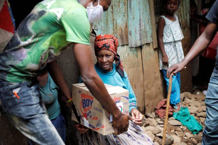An elderly woman receives a box of food donations given by an aid group to people in need in a poor section of Nairobi, Kenya, April 14, 2020, during the coronavirus pandemic. U.S.-based aid groups are providing funding and other support to communities most vulnerable to COVID-19 around globe. (CNS photo/Baz Ratner, Reuters) 