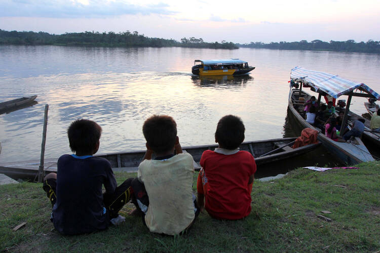 Kukama boys watch boats on the Amazon's Maranon River near Dos de Mayo in Peru's Loreto region. As the 2020 COVID-19 pandemic increasingly exposes fault lines between the rich and poor, the eight bishops of Peru's Amazonian region have urged the government to pay particular attention to the needs of indigenous people. (CNS photo/Barbara Fraser) 