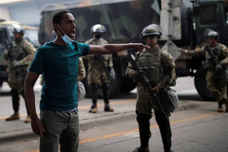 A protestor in Minneapolis gestures near National Guard members on May 29, 2020, arriving in the aftermath of a protest over the death of George Floyd, an African American, while in the custody of a white police officer. (CNS photo/Carlos Barria, Reuters) 