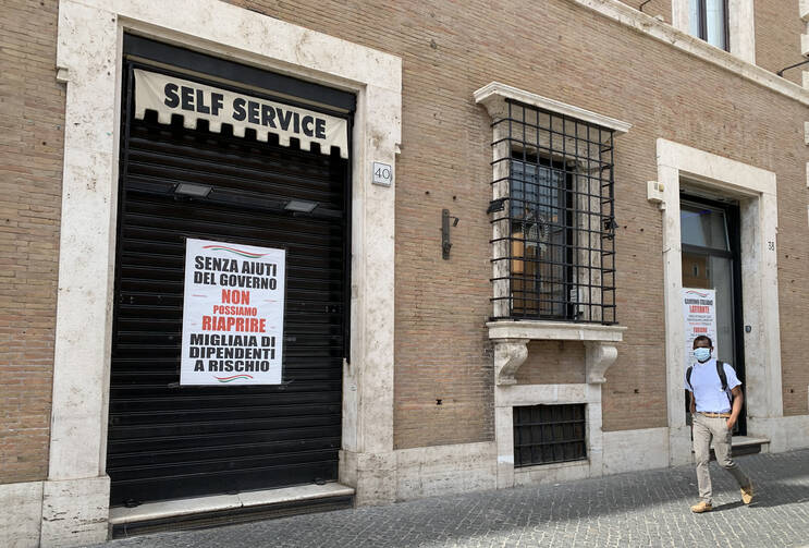 A man walks past a coffee bar and cafeteria on the Via della Conciliazione near the Vatican June 9, 2020. The sign in the window says, "Without government help, we cannot reopen. Thousands of employees at risk." (CNS photo/Cindy Wooden) 